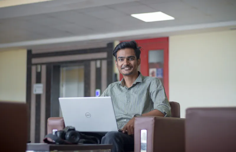 Young founder smiling while working on a laptop in an office